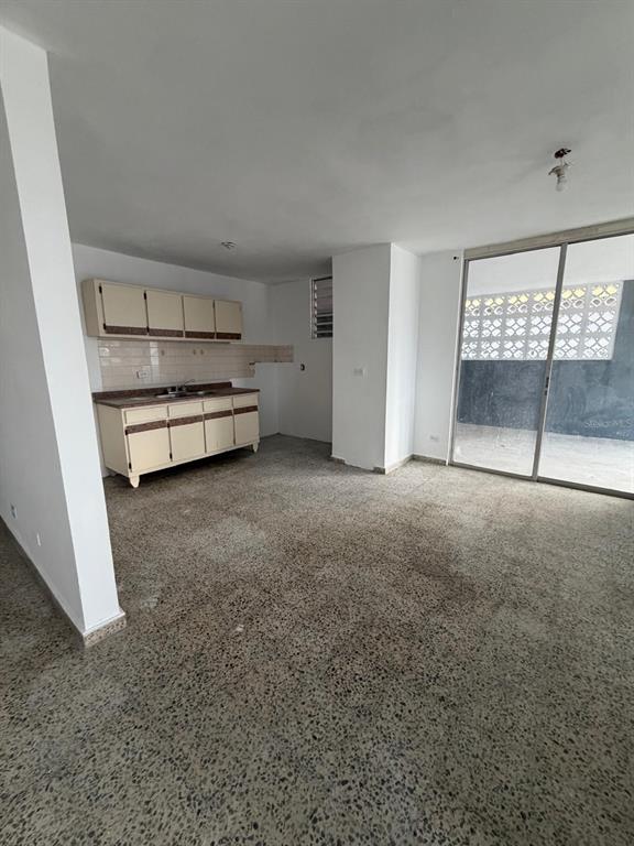 An open-concept kitchen and living area features terrazzo flooring, white walls, and a sliding glass door — Villa Carolina 205-13 N 510, CAROLINA, PR