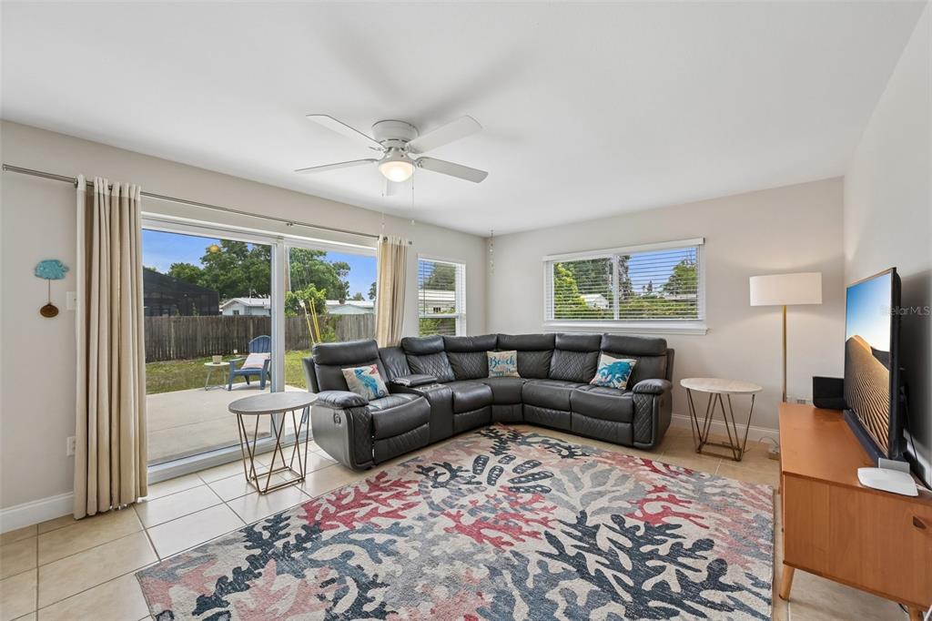 A living room features a large gray sectional sofa, a patterned rug, and sliding doors — 5005 BEE RIDGE ROAD, SARASOTA, FL