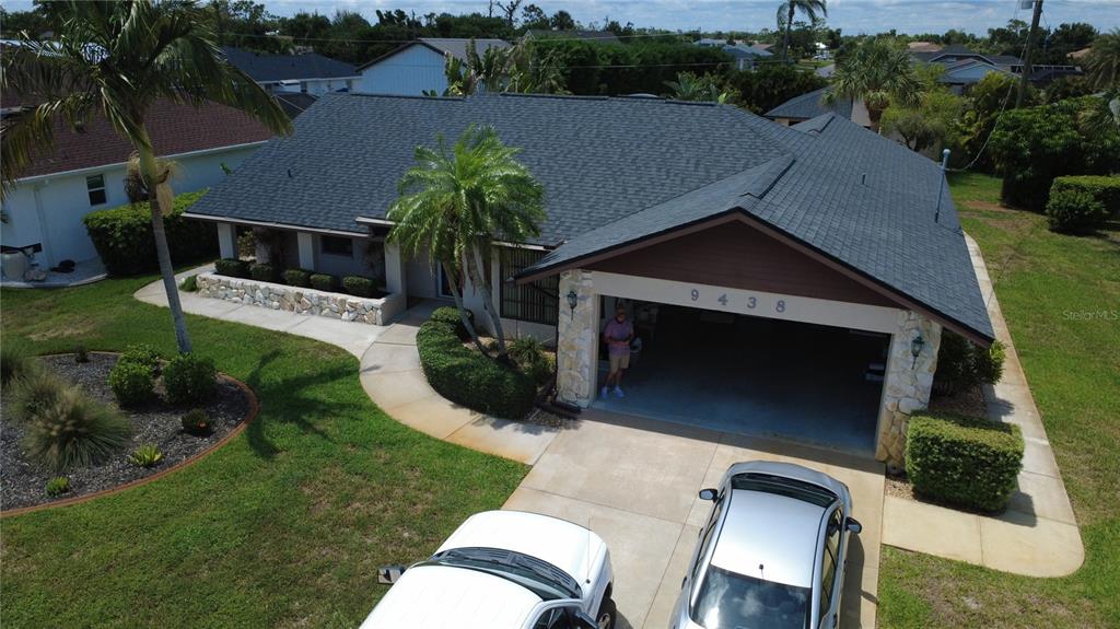 A red SUV is parked inside an open-air garage attached to a residential home — 9438 CRUGAR, ENGLEWOOD, FL