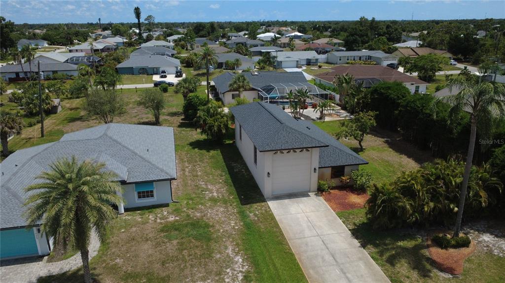 An aerial view shows a single-story house with a dark shingled roof and stone accents — 9438 CRUGAR, ENGLEWOOD, FL