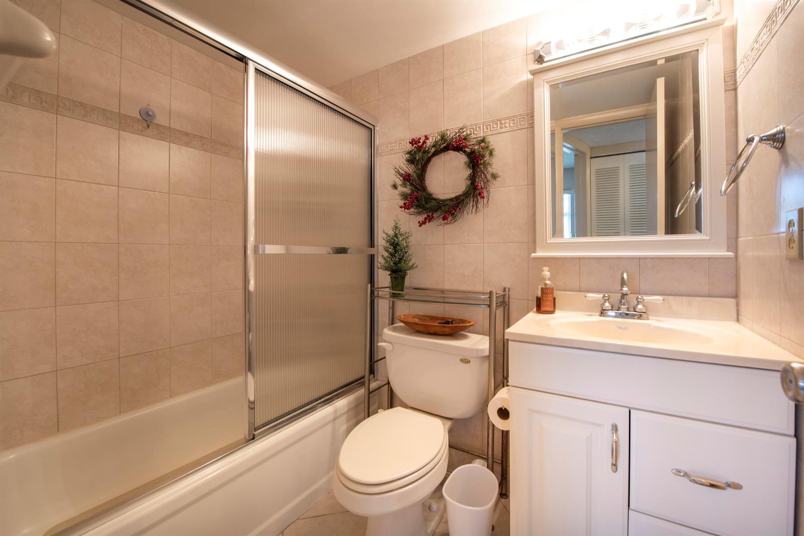 A bathroom features a shower-tub combination, a white vanity, and a toilet with shelving above — 1391 S Ocean Boulevard # 308, Pompano Beach FL 33062, POMPANO BEACH, FL