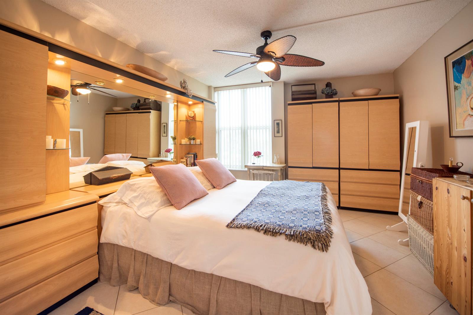 A bedroom with a bed, large wooden wardrobes, a ceiling fan, and tiled flooring — 1391 S Ocean Boulevard # 308, Pompano Beach FL 33062, POMPANO BEACH, FL