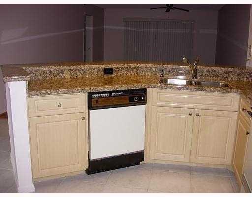 A kitchen features light wood cabinets, granite countertops, a stainless steel sink, and a dishwasher — 2205 S Cypress Bend Drive # 307, Pompano Beach FL 33069, POMPANO BEACH, FL