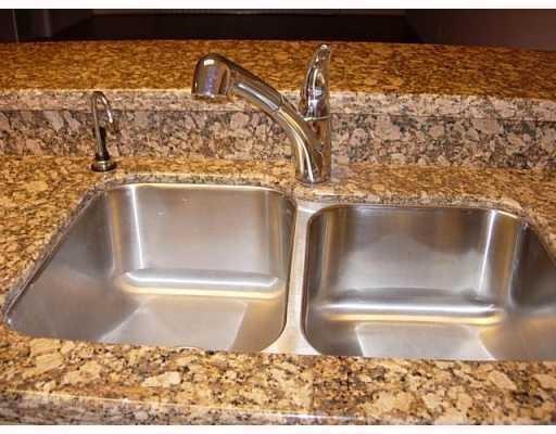 A stainless steel double-basin kitchen sink with a chrome faucet set in granite countertops — 2205 S Cypress Bend Drive # 307, Pompano Beach FL 33069, POMPANO BEACH, FL