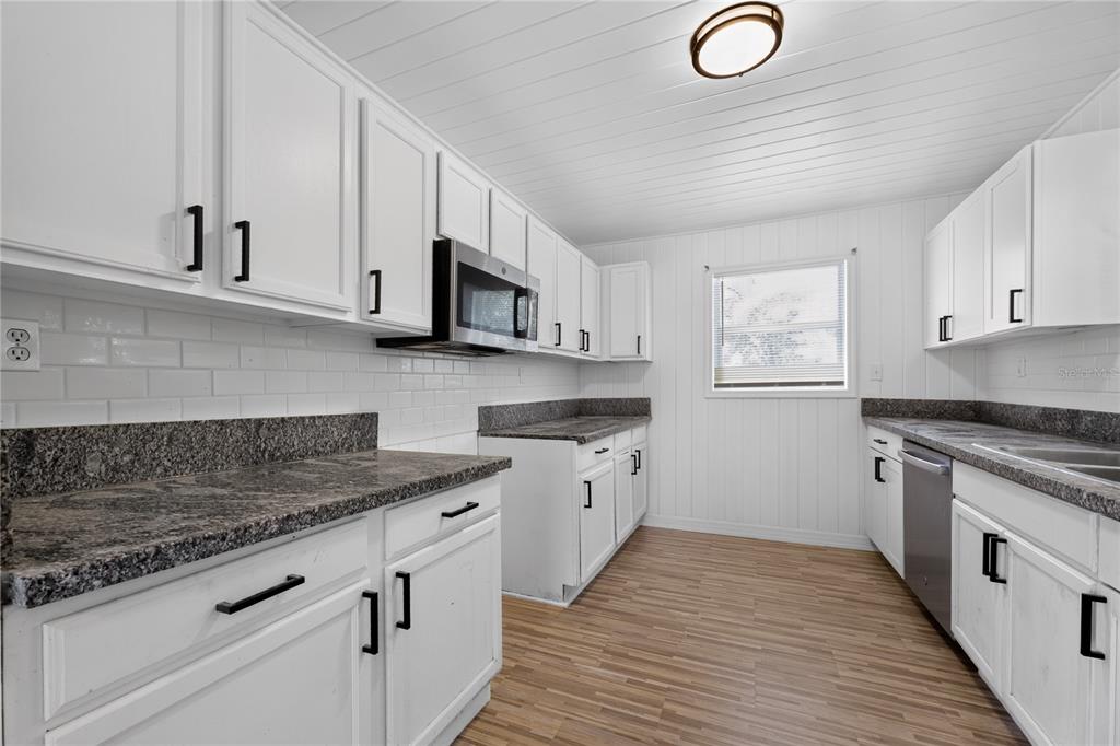 A kitchen with white cabinets, granite countertops, a subway tile backsplash, and wood-look flooring — 3636 TURTON AVENUE, JACKSONVILLE, FL