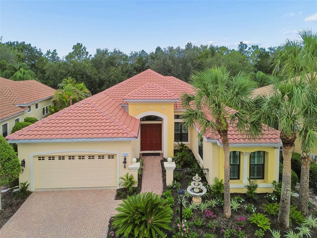 A yellow single-story house with a red tile roof and a brick driveway — 7222 LAKE FOREST GLEN, BRADENTON, FL