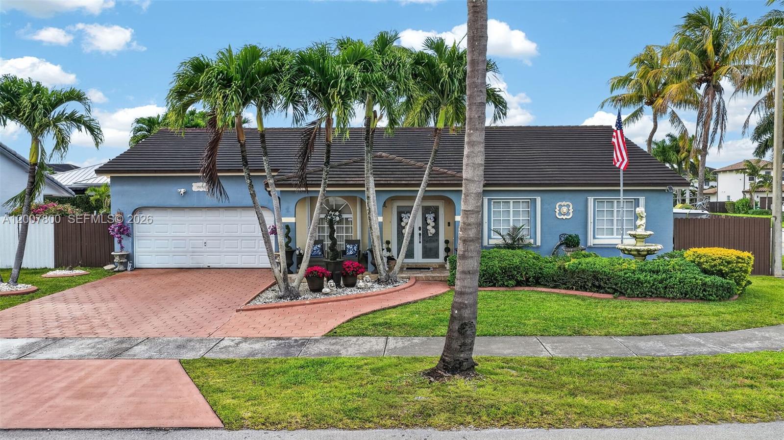 A blue single-story house features a red paved driveway, palm trees, and a front lawn — 15201 SW 177th Ter, Miami FL 33187, MIAMI, FL