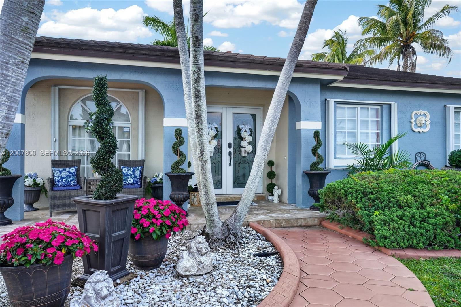 A single-story blue house with a white garage door, palm trees, and a front fountain — 15201 SW 177th Ter, Miami FL 33187, MIAMI, FL