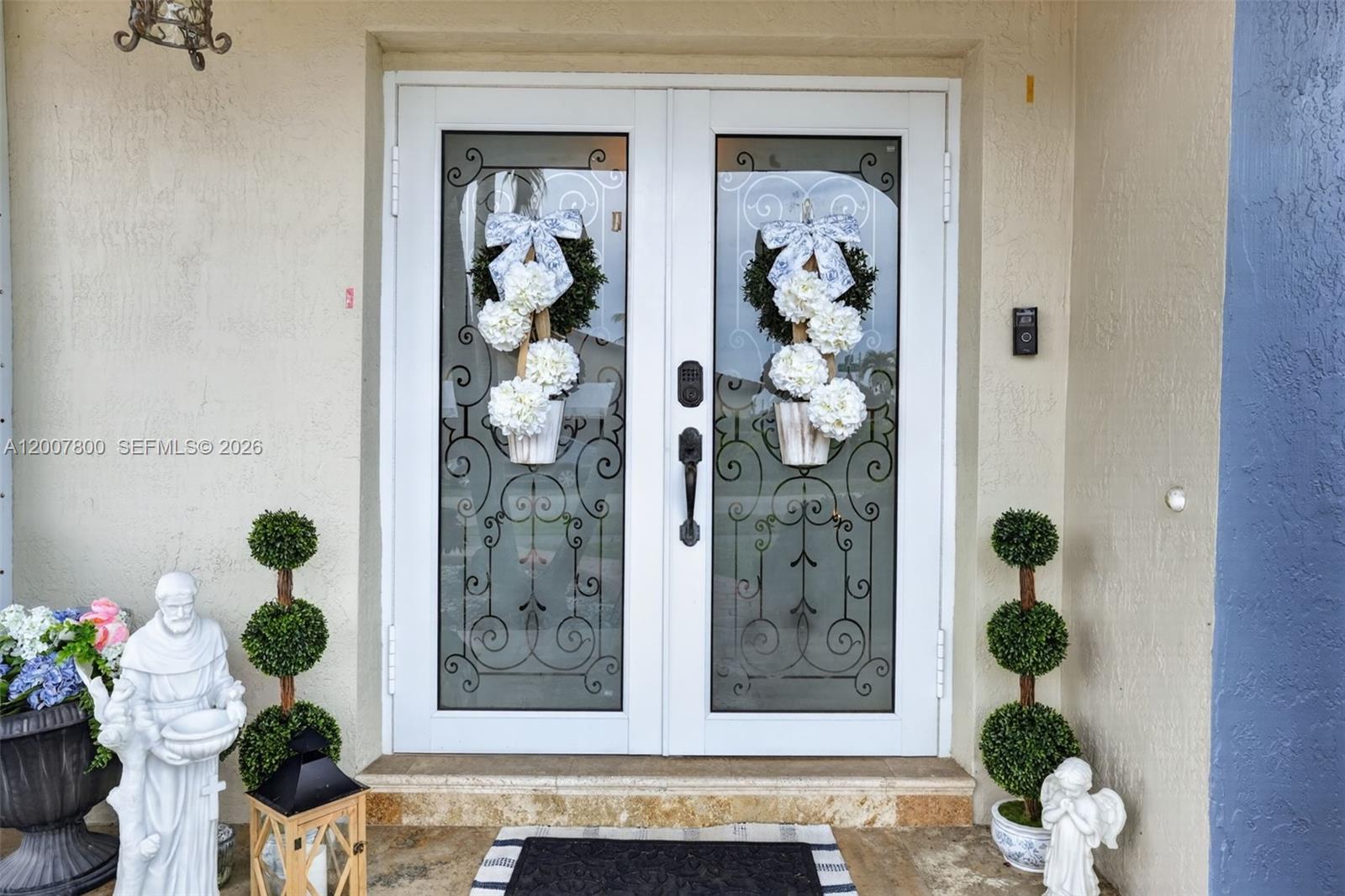 A blue house exterior features a stone walkway, potted plants, and a double-door entrance — 15201 SW 177th Ter, Miami FL 33187, MIAMI, FL
