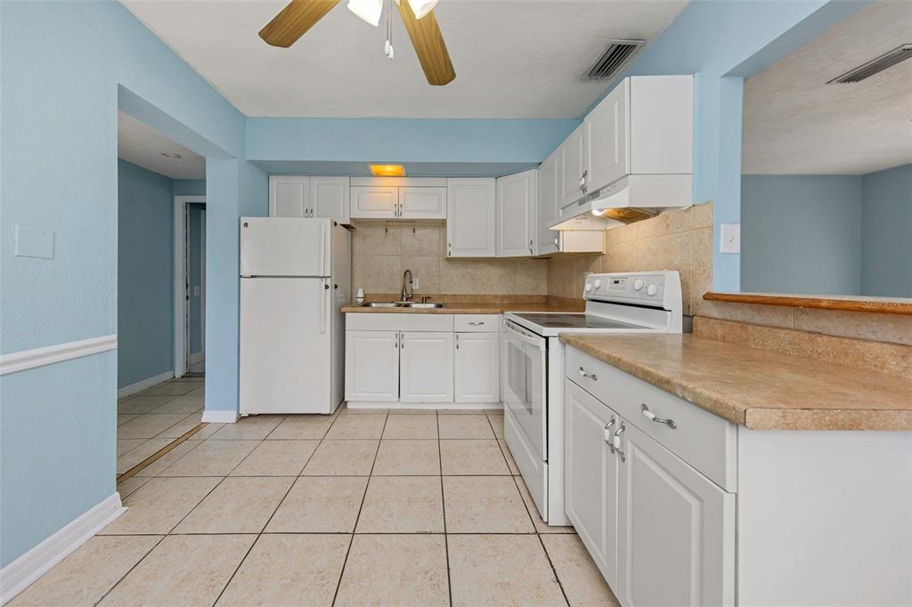 A kitchen with white cabinets, light-colored tile flooring, and a white refrigerator and stove — 5326 BERKLEY ROAD, NEW PORT RICHEY, FL
