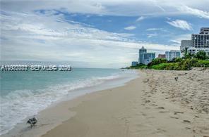 A sandy beach stretches along the ocean toward high-rise buildings under a cloudy sky — 5555 Collins Ave # 15W, Miami Beach FL 33140, MIAMI BEACH, FL