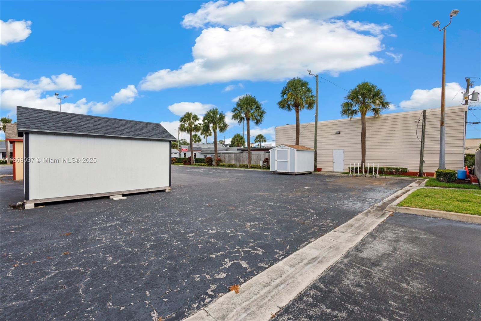 An asphalt parking lot features two storage sheds and several palm trees under a blue sky — 2402 S US HWY 1, Fort Pierce FL 34982, FORT PIERCE, FL