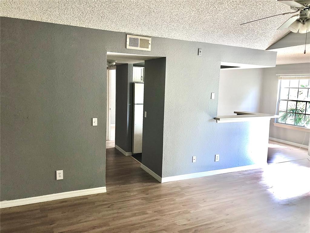 A living room with gray walls, wood-look flooring, a ceiling fan, and a kitchen pass-through — 1037 S HIAWASSEE ROAD UNIT 2835, ORLANDO, FL