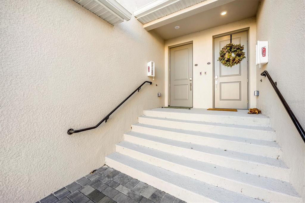 A set of concrete stairs leads up to two beige entry doors with handrails — 17770 BORACAY COURT UNIT 201, VENICE, FL