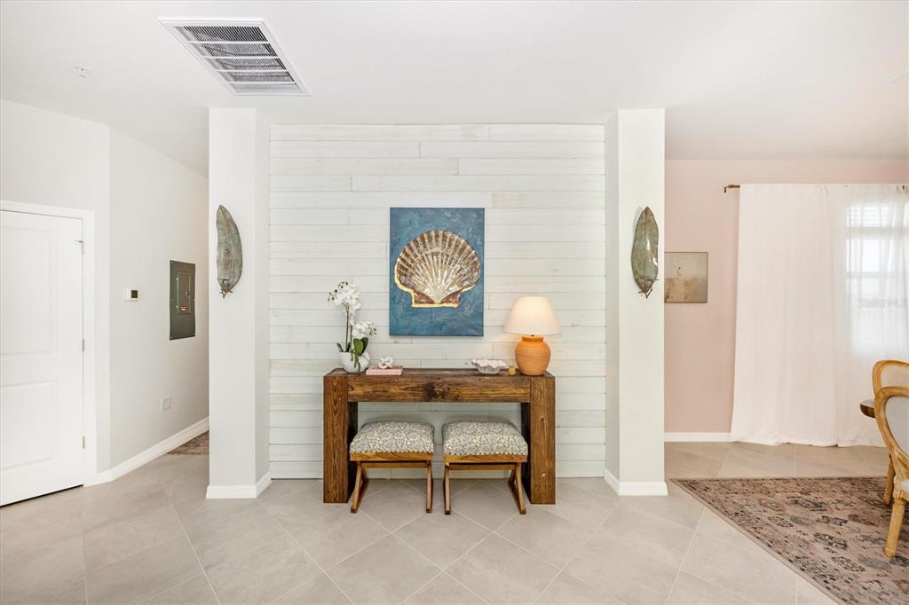 A foyer features a white shiplap accent wall, a wooden console table, and two stools — 17770 BORACAY COURT UNIT 201, VENICE, FL