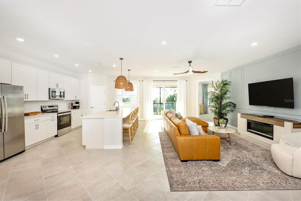 An open-concept kitchen and living area featuring white cabinetry, a kitchen island, and leather sofa — 17770 BORACAY COURT UNIT 201, VENICE, FL