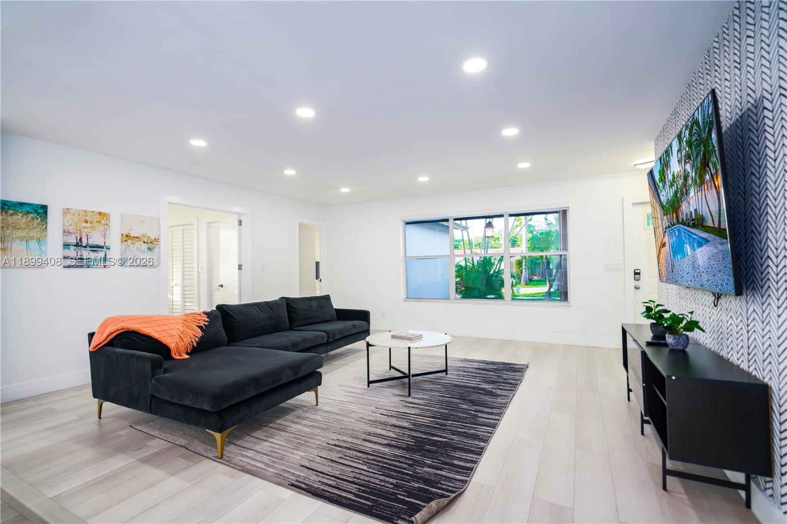 A living room features a black sectional sofa, a patterned rug, and a wall-mounted television — 1244 Garfield St, Hollywood FL 33019, HOLLYWOOD, FL