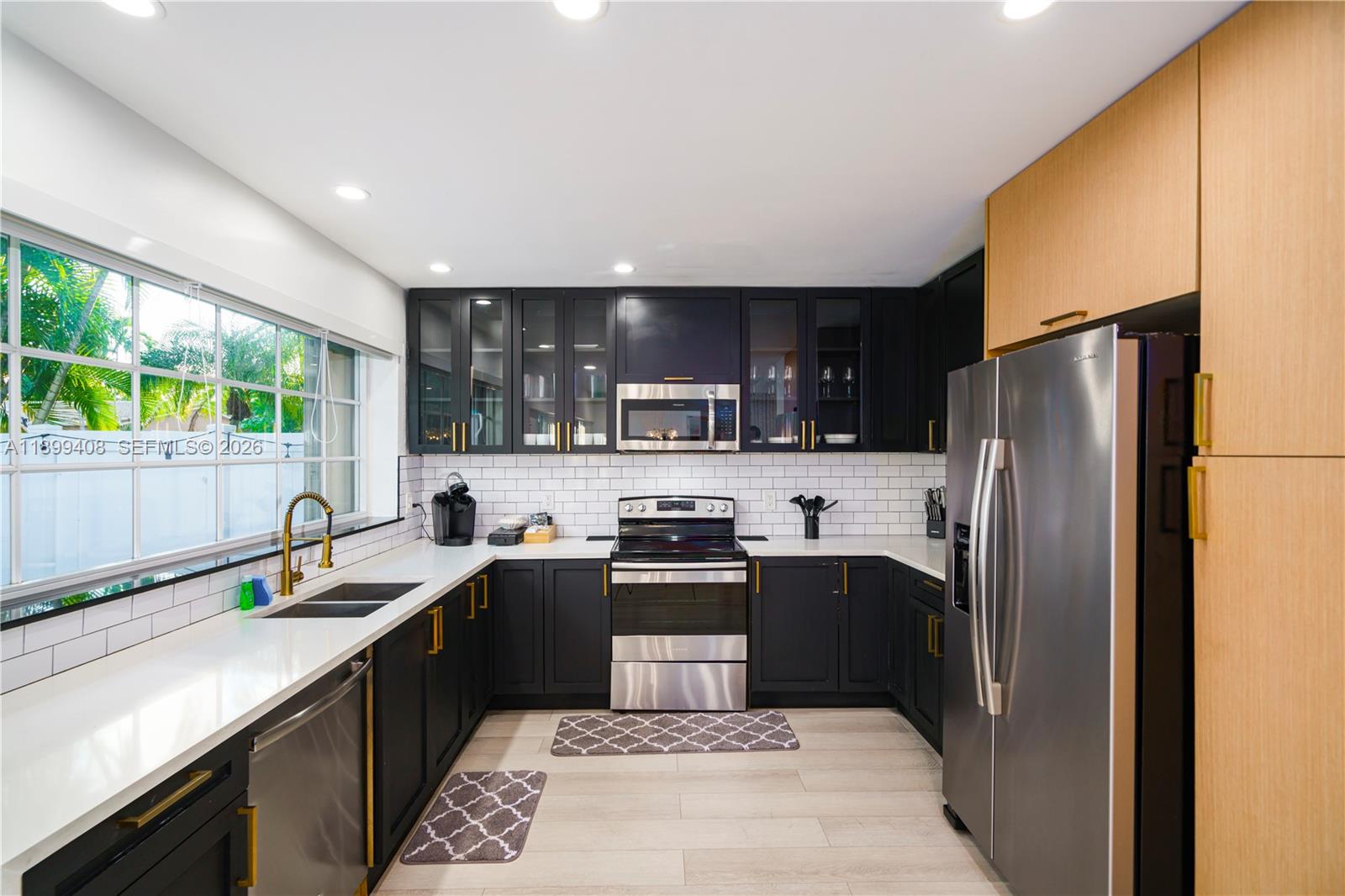 A kitchen features dark cabinets, stainless steel appliances, white countertops, and a subway tile backsplash — 1244 Garfield St, Hollywood FL 33019, HOLLYWOOD, FL