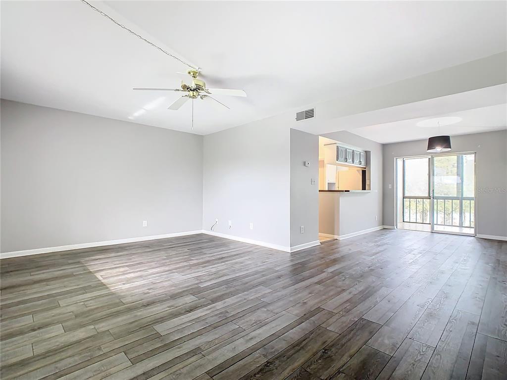 An open-concept living area features gray walls, wood-look flooring, a ceiling fan, and sliding doors — 1130 N LAKE PARKER AVENUE UNIT A302, LAKELAND, FL