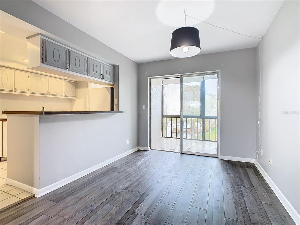 A dining area features dark wood-look flooring, gray walls, a breakfast bar, and sliding glass doors — 1130 N LAKE PARKER AVENUE UNIT A302, LAKELAND, FL