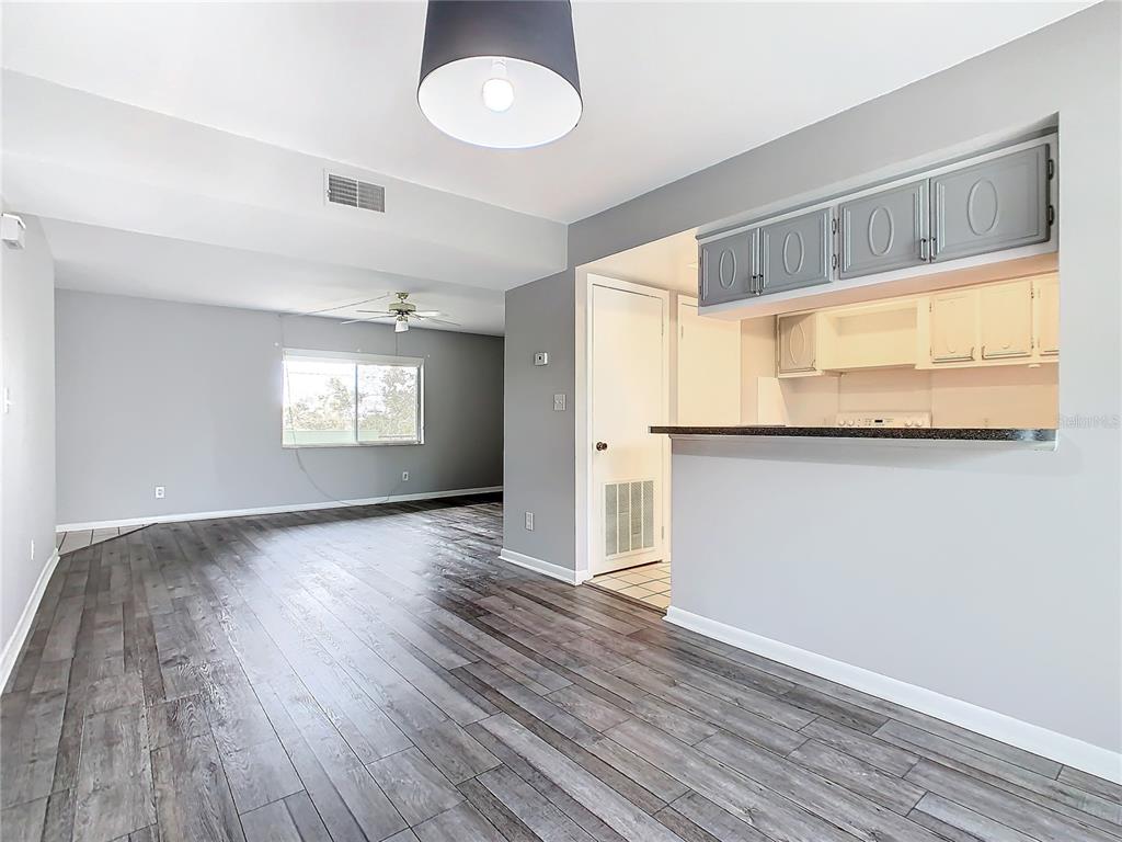 A living area with wood-look flooring leads to a kitchen with a breakfast bar — 1130 N LAKE PARKER AVENUE UNIT A302, LAKELAND, FL