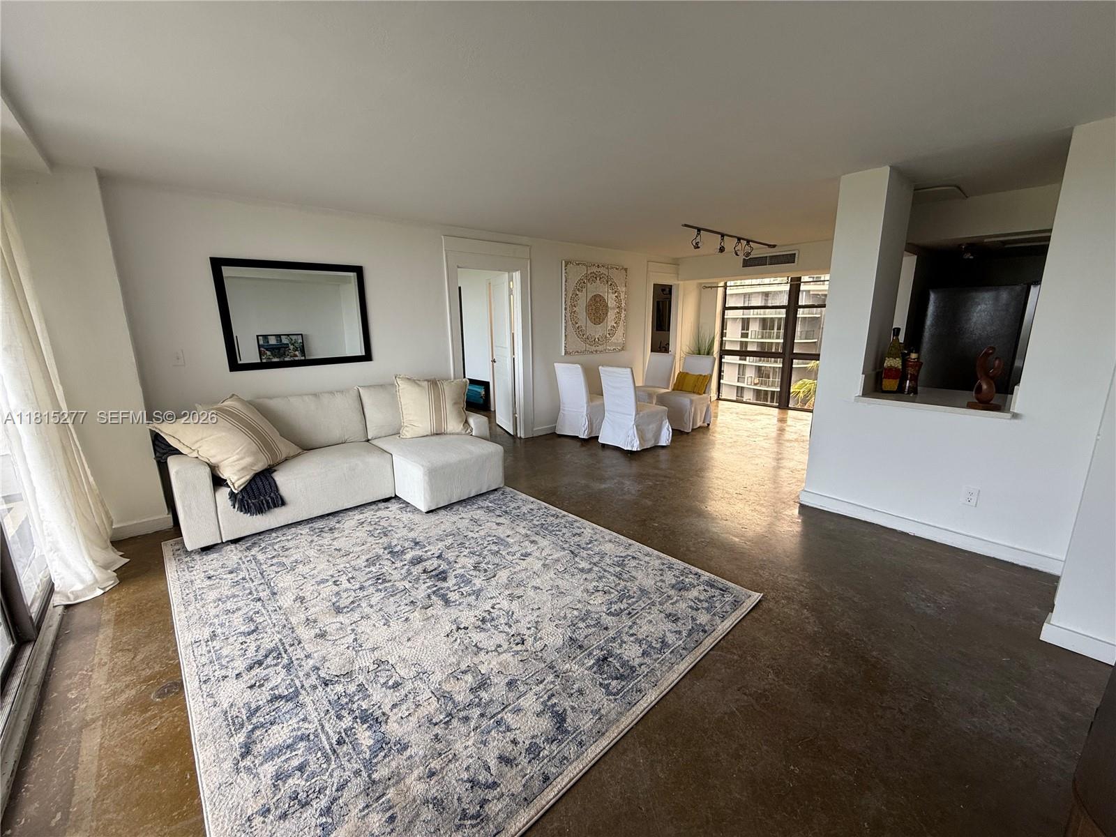 A living and dining area features a white sectional sofa, area rug, and concrete floors — 5701 Biscayne Blvd # 701, Miami FL 33137, MIAMI, FL