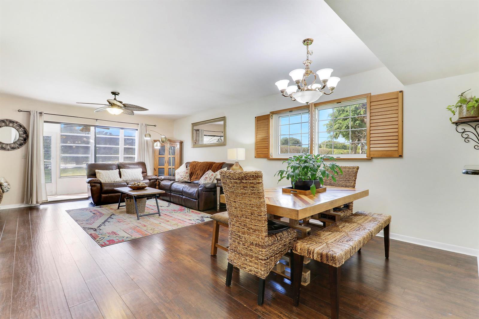 A living and dining area features dark wood floors, leather sofas, and a wicker dining set — 1700 Dover Road # 106a, Delray Beach FL 33445, DELRAY BEACH, FL