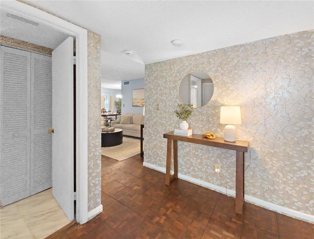 A foyer with patterned wallpaper and a wooden console table leads into a living room — 553 FAIRWAYS CIRCLE UNIT B, OCALA, FL