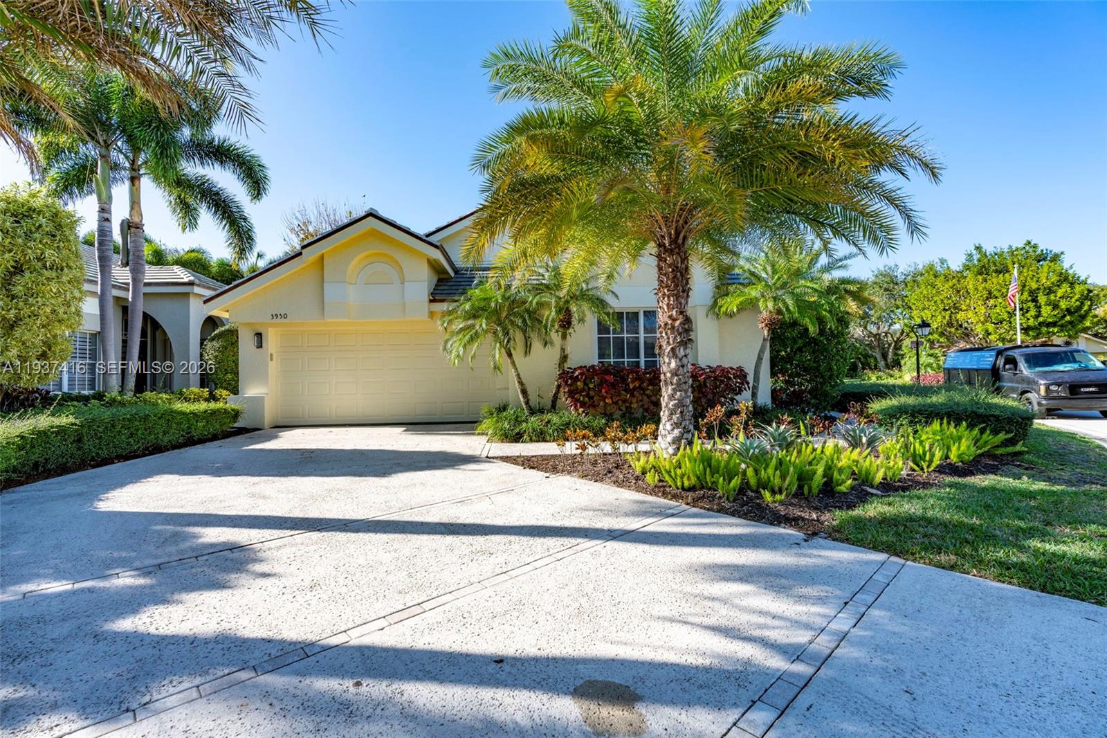 A yellow single-story house features a concrete driveway, palm trees, and a two-car garage — 3950 Shearwater Dr, Jupiter FL 33477, JUPITER, FL