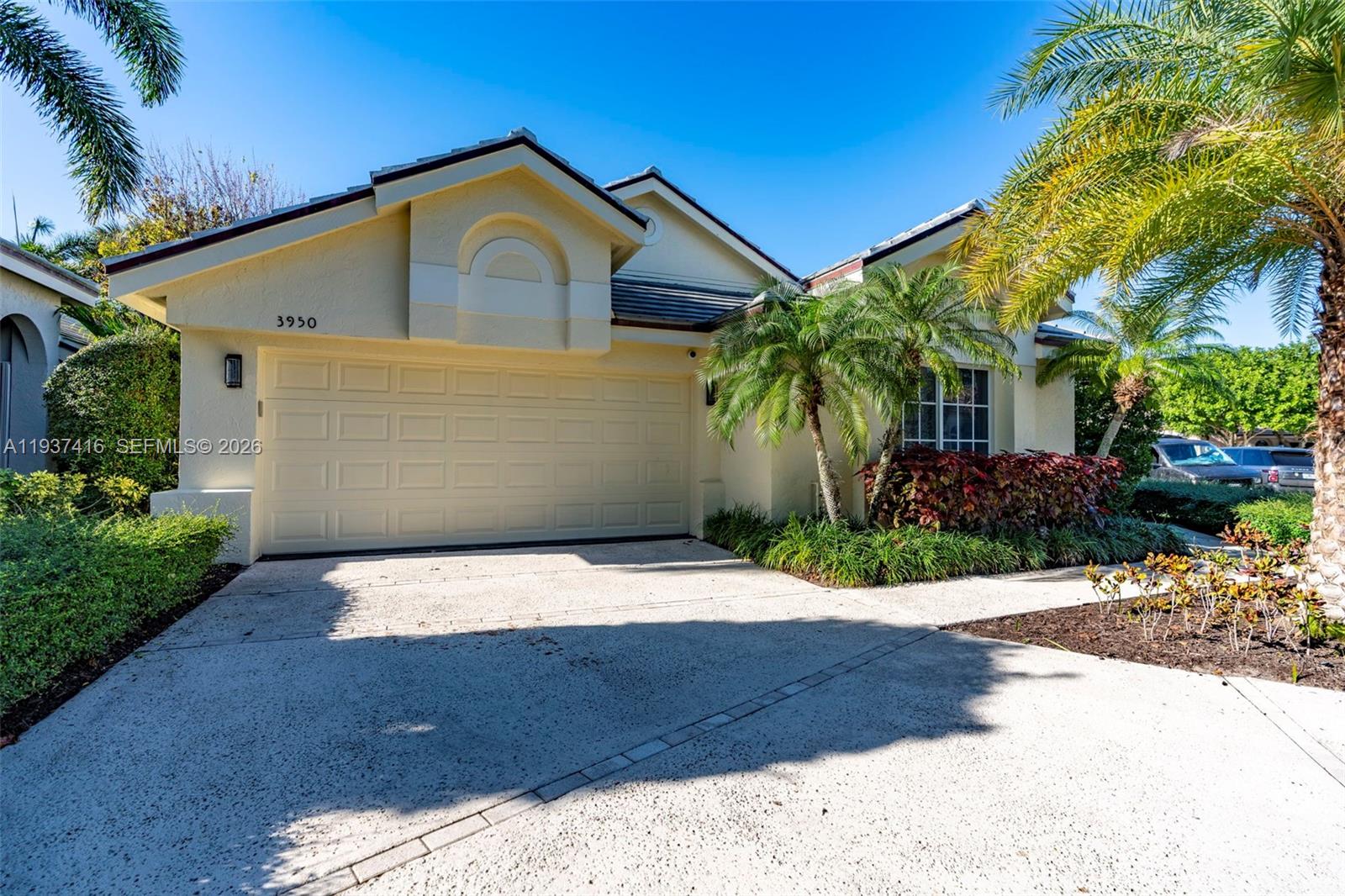 A single-story house with a beige stucco exterior, a two-car garage, and palm trees — 3950 Shearwater Dr, Jupiter FL 33477, JUPITER, FL