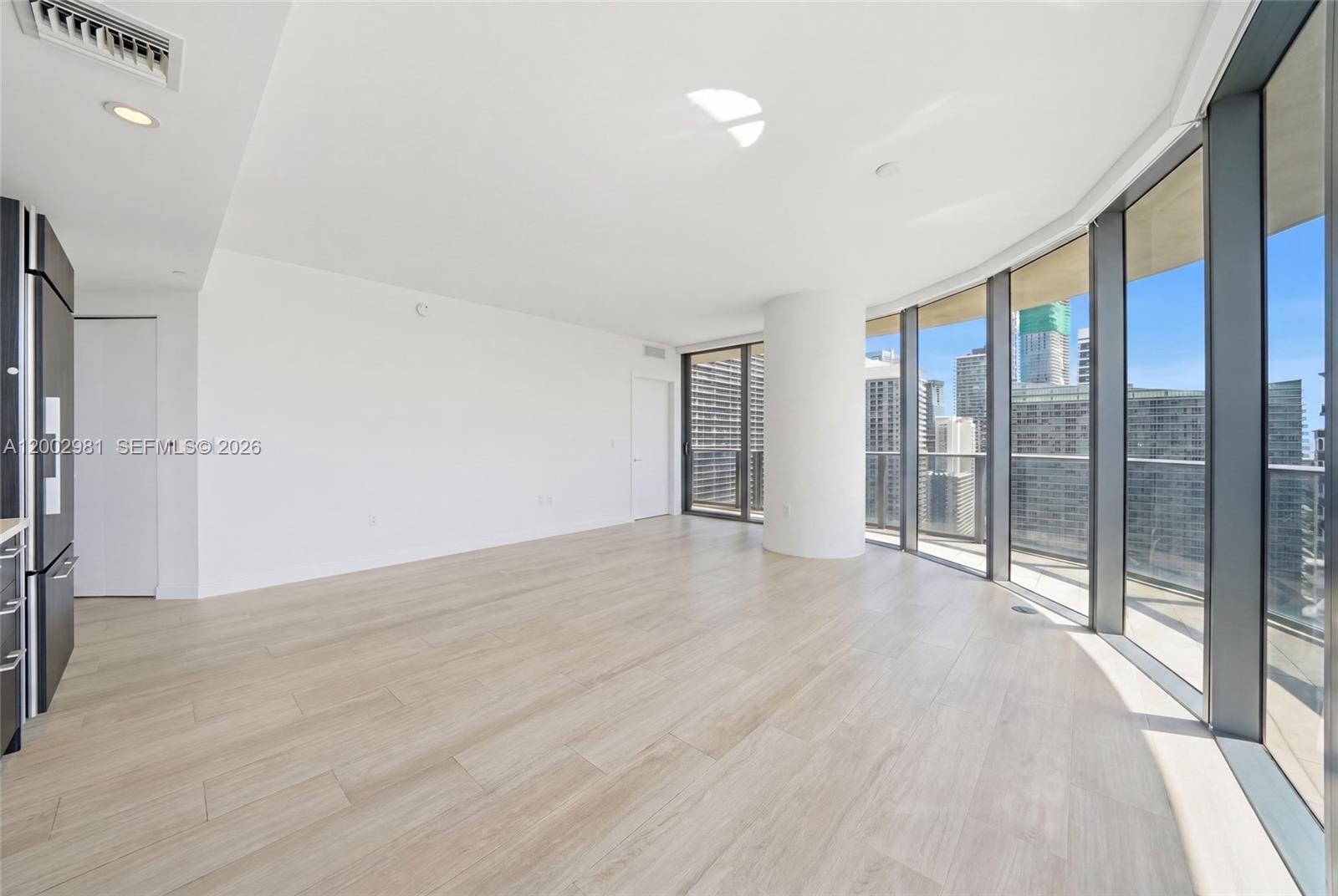 An empty room with light wood floors, a white pillar, and floor-to-ceiling windows — 55 SW 9th St # 3106, Miami FL 33130, MIAMI, FL