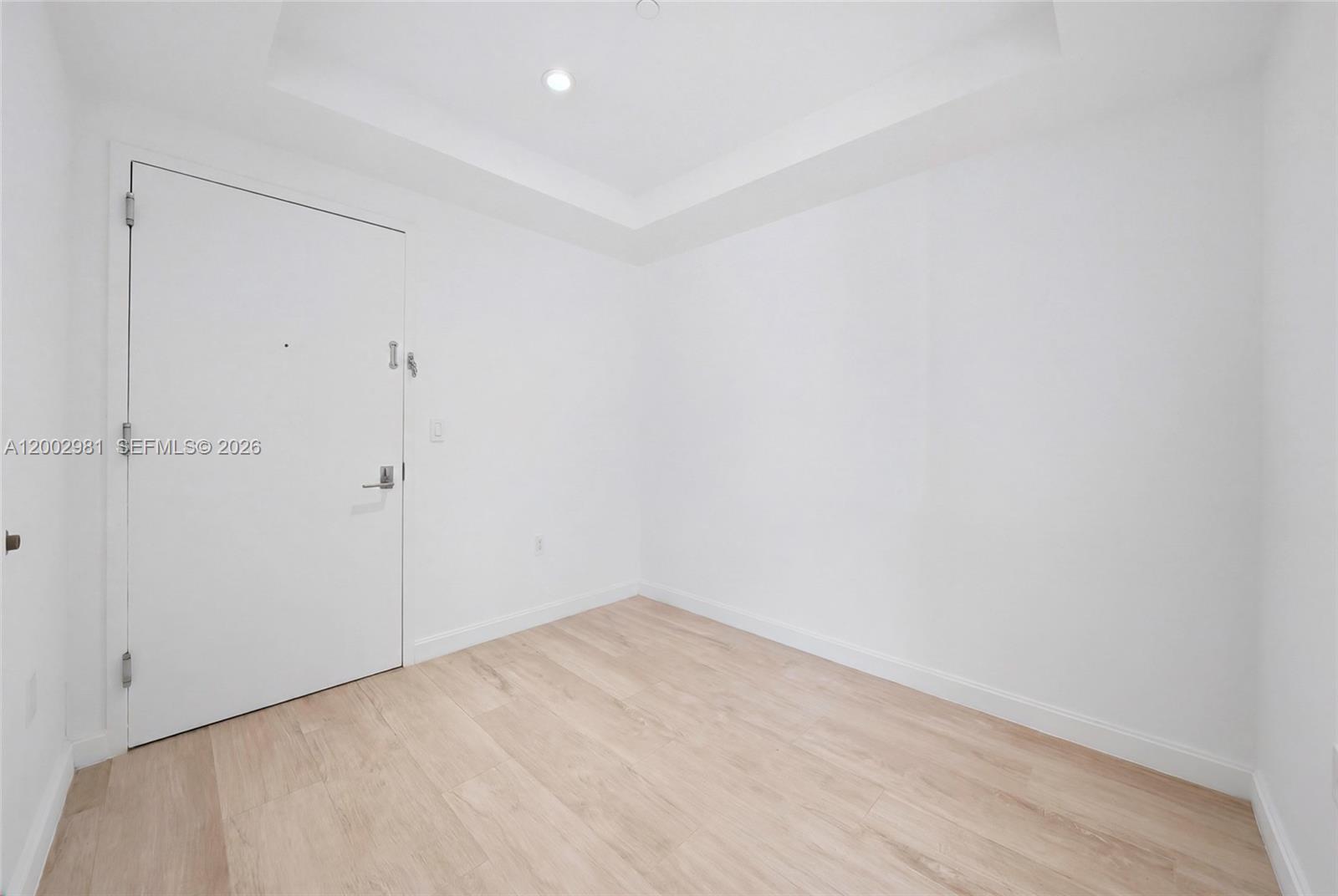 An empty room features white walls, light wood-look flooring, and a white entry door — 55 SW 9th St # 3106, Miami FL 33130, MIAMI, FL