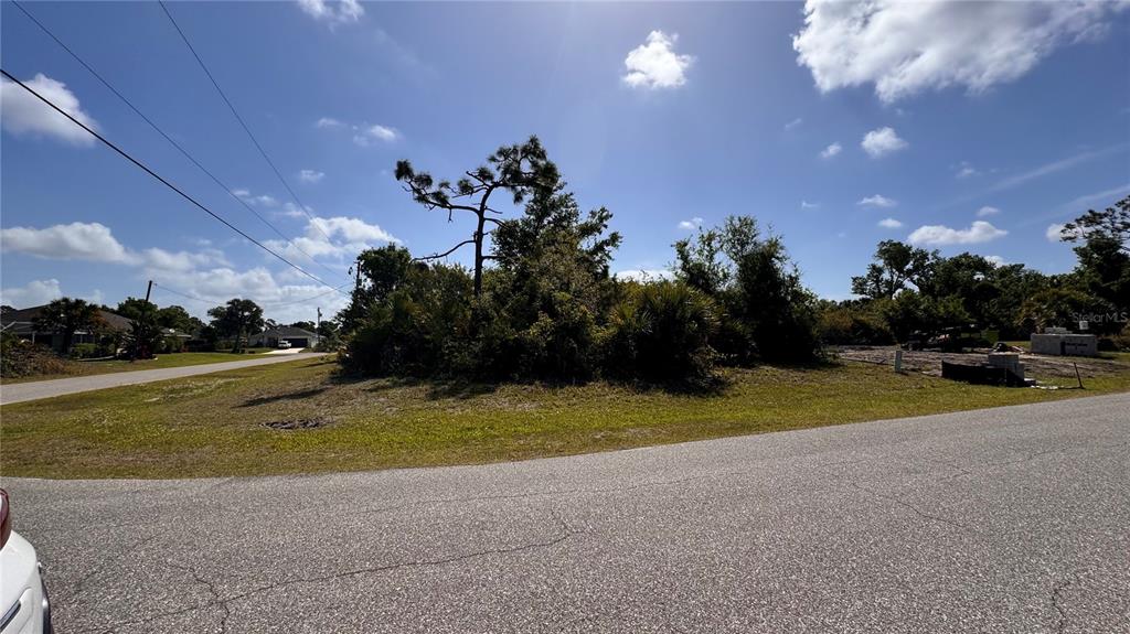 A vacant, grassy residential lot with trees and shrubs sits at a street corner — 116 AUSTRALIAN DRIVE, ROTONDA WEST, FL