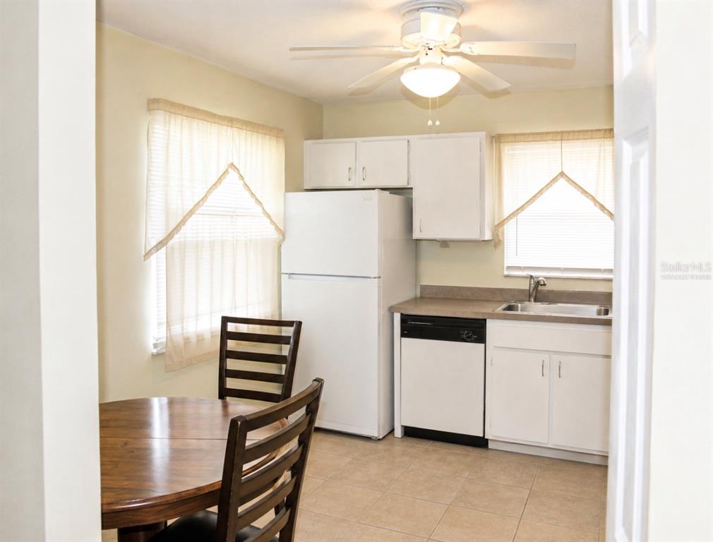 A kitchen with white cabinets, a white refrigerator, a dishwasher, and a small dining table — 7717 MITCHELL RANCH ROAD, NEW PORT RICHEY, FL