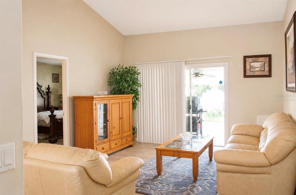 A living room with beige walls, tile floors, two leather sofas, and a wooden cabinet — 7717 MITCHELL RANCH ROAD, NEW PORT RICHEY, FL