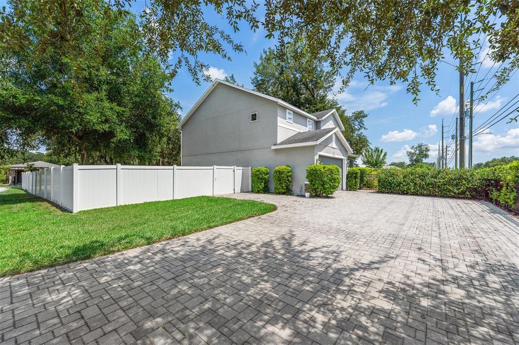 A gray two-story house features a paved driveway, a white fence, and manicured landscaping — 4723 CONWAY ROAD, ORLANDO, FL