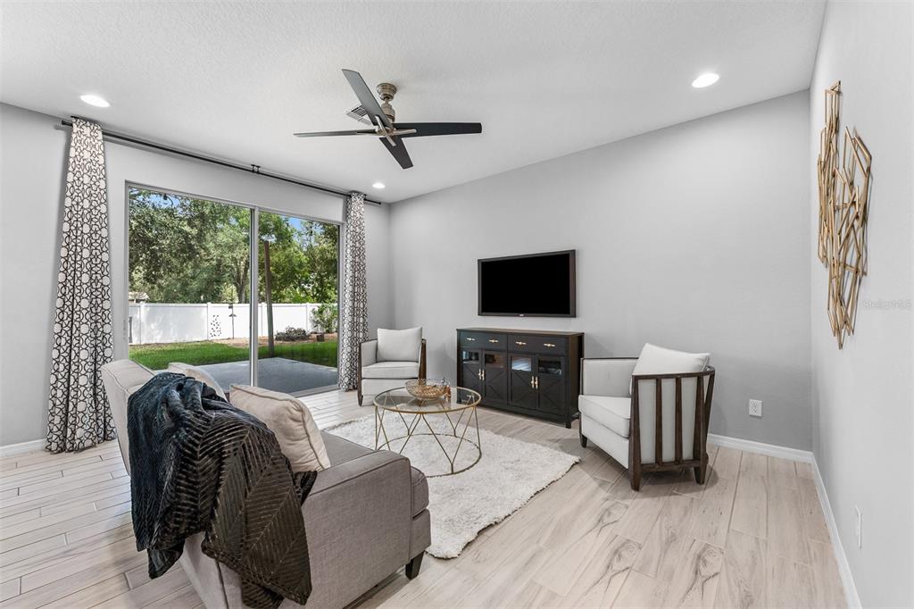 A living room features a gray sofa, two armchairs, a television, and sliding glass doors — 4723 CONWAY ROAD, ORLANDO, FL