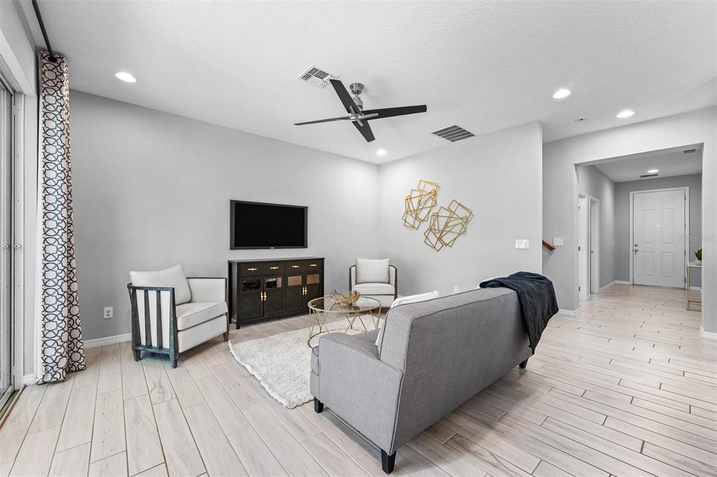 A living room features light wood-look tile flooring, a gray sofa, and two armchairs — 4723 CONWAY ROAD, ORLANDO, FL