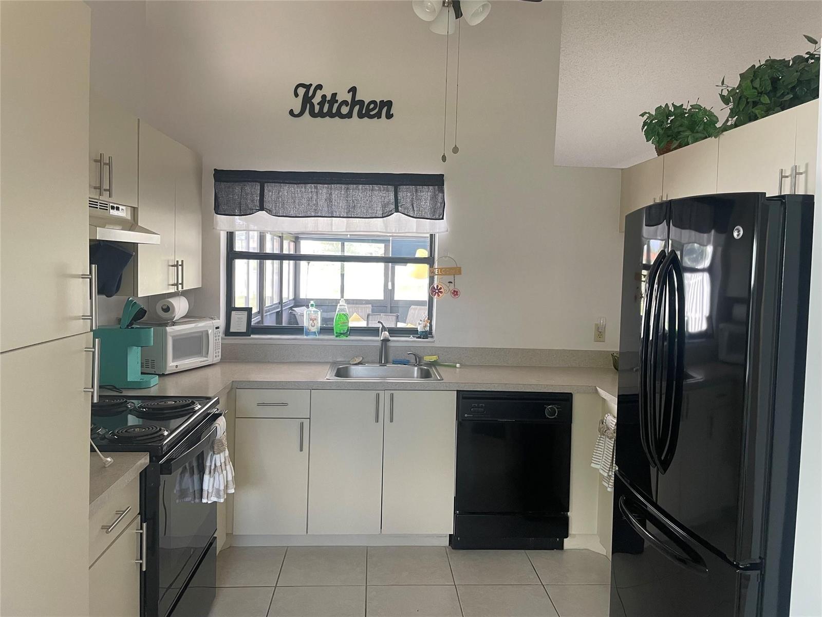A kitchen features light cabinets, black appliances, a window over the sink, and tile flooring — 5675 Northpointe Lane, Boynton Beach FL 33437, BOYNTON BEACH, FL
