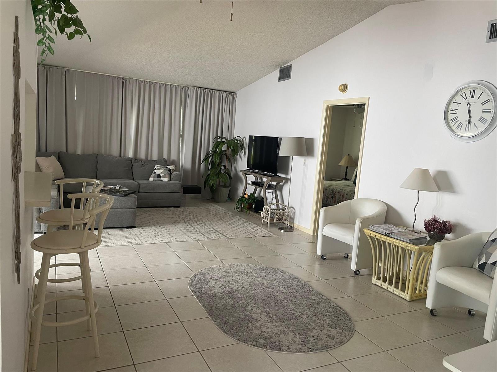 A living room with tile flooring, a gray sectional sofa, and a white accent chair — 5675 Northpointe Lane, Boynton Beach FL 33437, BOYNTON BEACH, FL