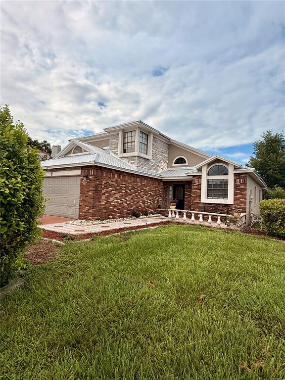 A two-story house features a brick facade, stone accents, and a metal roof — 3145 PELL MELL DRIVE, ORLANDO, FL
