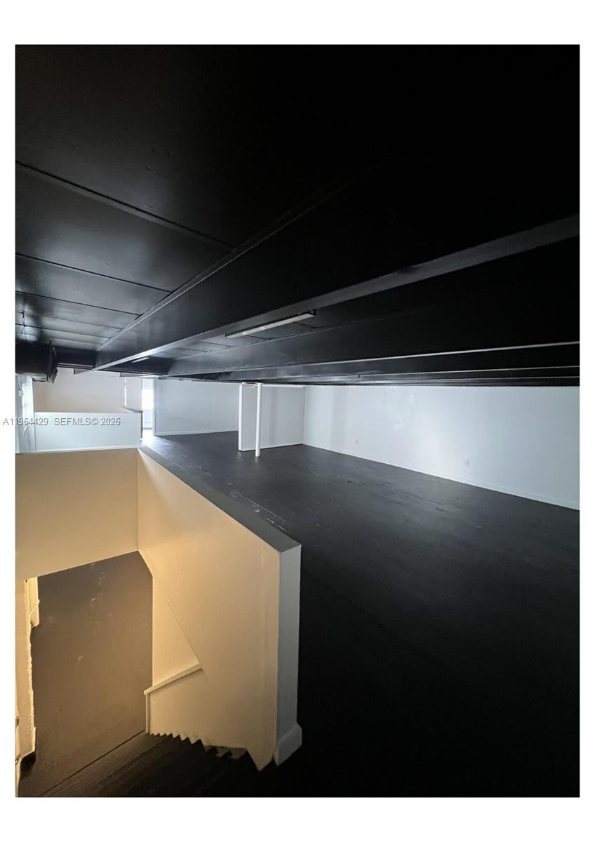 A loft area features dark wood flooring, black ceiling beams, and white walls — 1155 SW 6th St, Miami FL 33130, MIAMI, FL