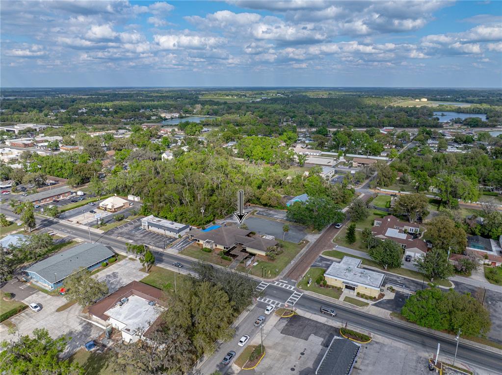 An aerial view shows a commercial building with a parking lot in a suburban area — 13924 7TH STREET, DADE CITY, FL
