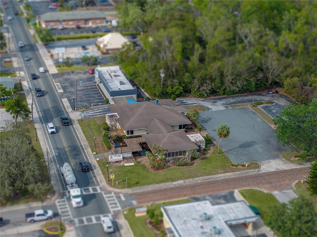 An aerial view shows a commercial building with a large parking lot and surrounding greenery — 13924 7TH STREET, DADE CITY, FL