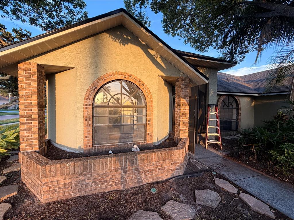 The exterior of a house features a brick planter, arched windows, and a front entryway — 1015 CALLE ROSA PLACE, SUN CITY CENTER, FL