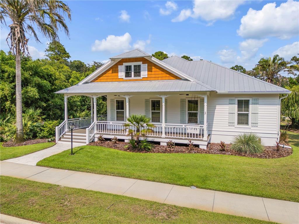 A white house with a metal roof, front porch, and orange gable siding — 1902 KINGS, NEW SMYRNA BEACH, FL