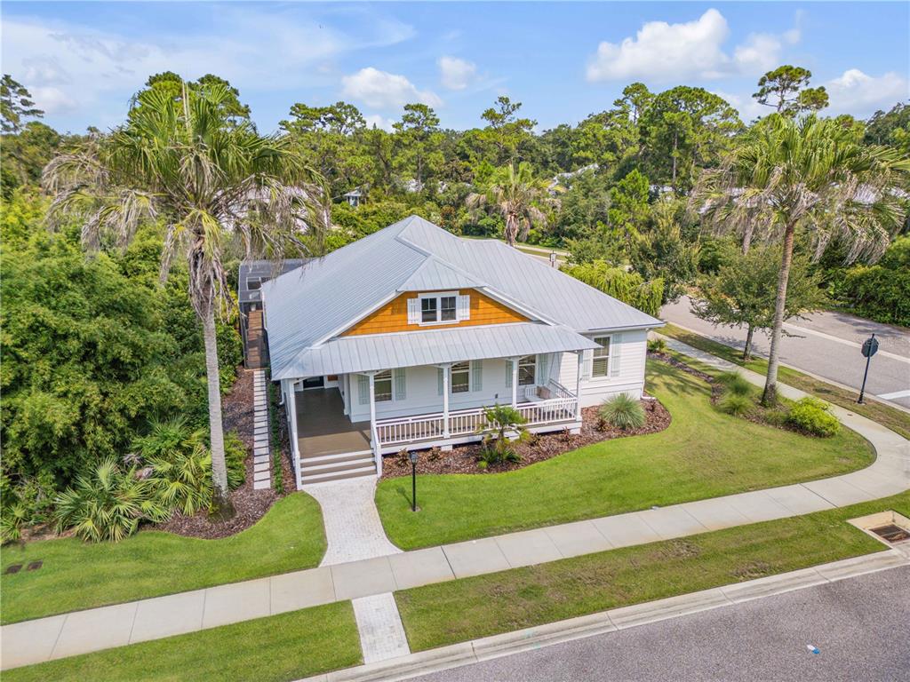 An elevated white house with a metal roof and a front porch sits near a road — 1902 KINGS, NEW SMYRNA BEACH, FL