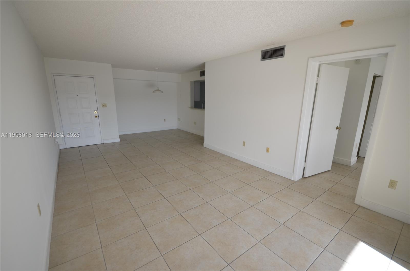 An empty room features beige tile flooring, white walls, and a doorway leading to another area — 15201 SW 80th St # 207, Miami FL 33193, MIAMI, FL