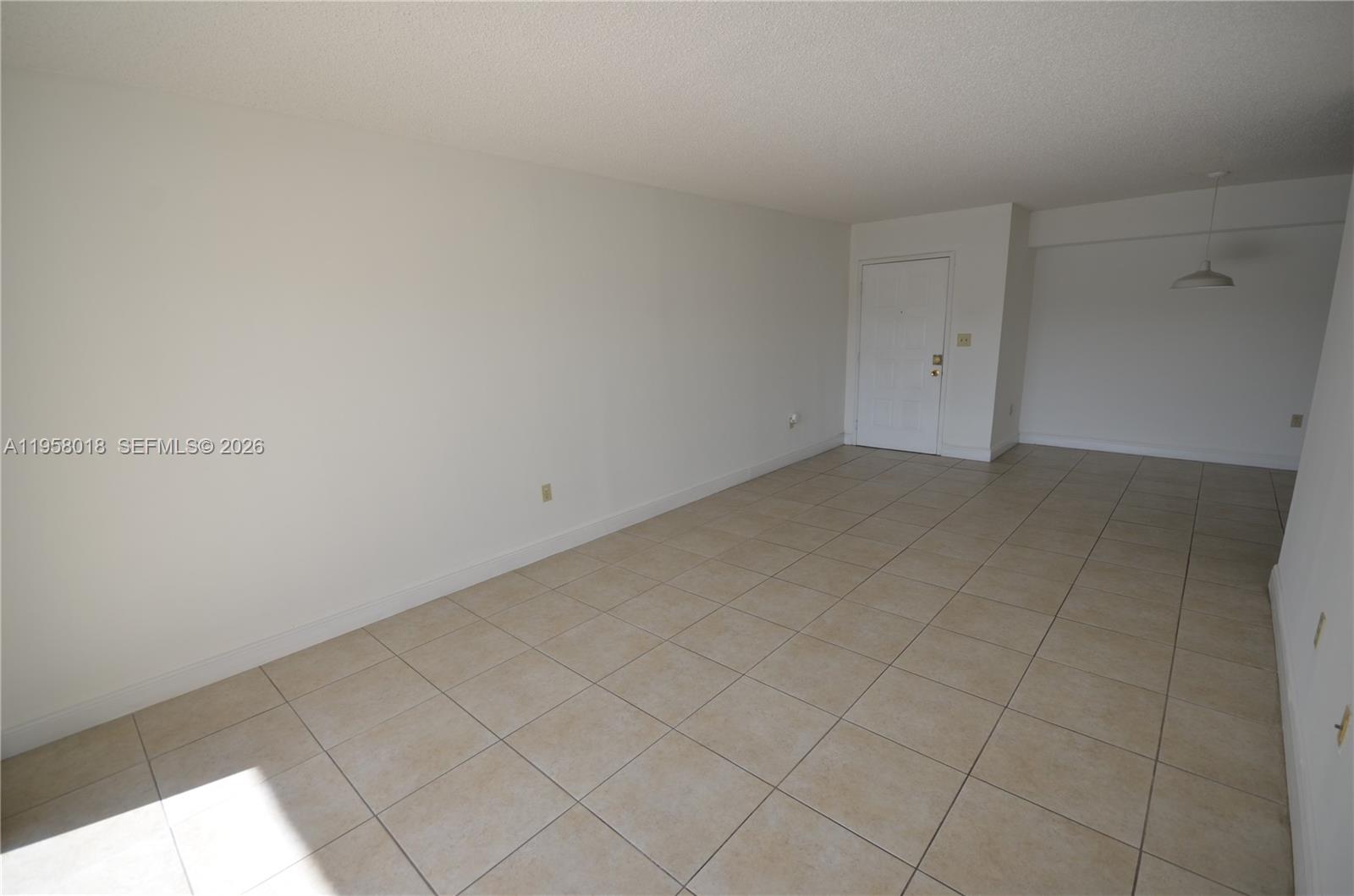 An empty room features white walls, beige tile flooring, and a white entry door — 15201 SW 80th St # 207, Miami FL 33193, MIAMI, FL