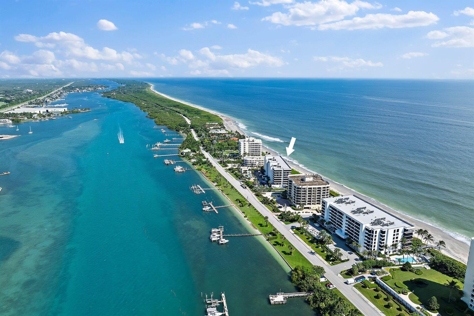 An aerial view shows a coastal condominium complex situated between the ocean and a bay — 19900 Beach Road # 201, Jupiter FL 33469, JUPITER, FL